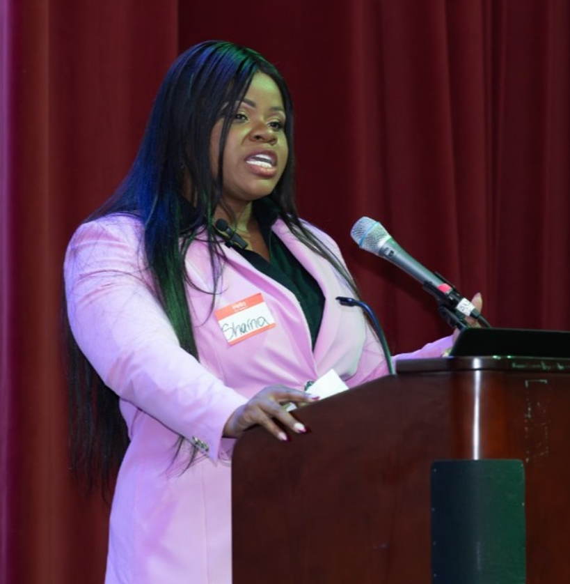 Sharna Barnes speaking at a podium